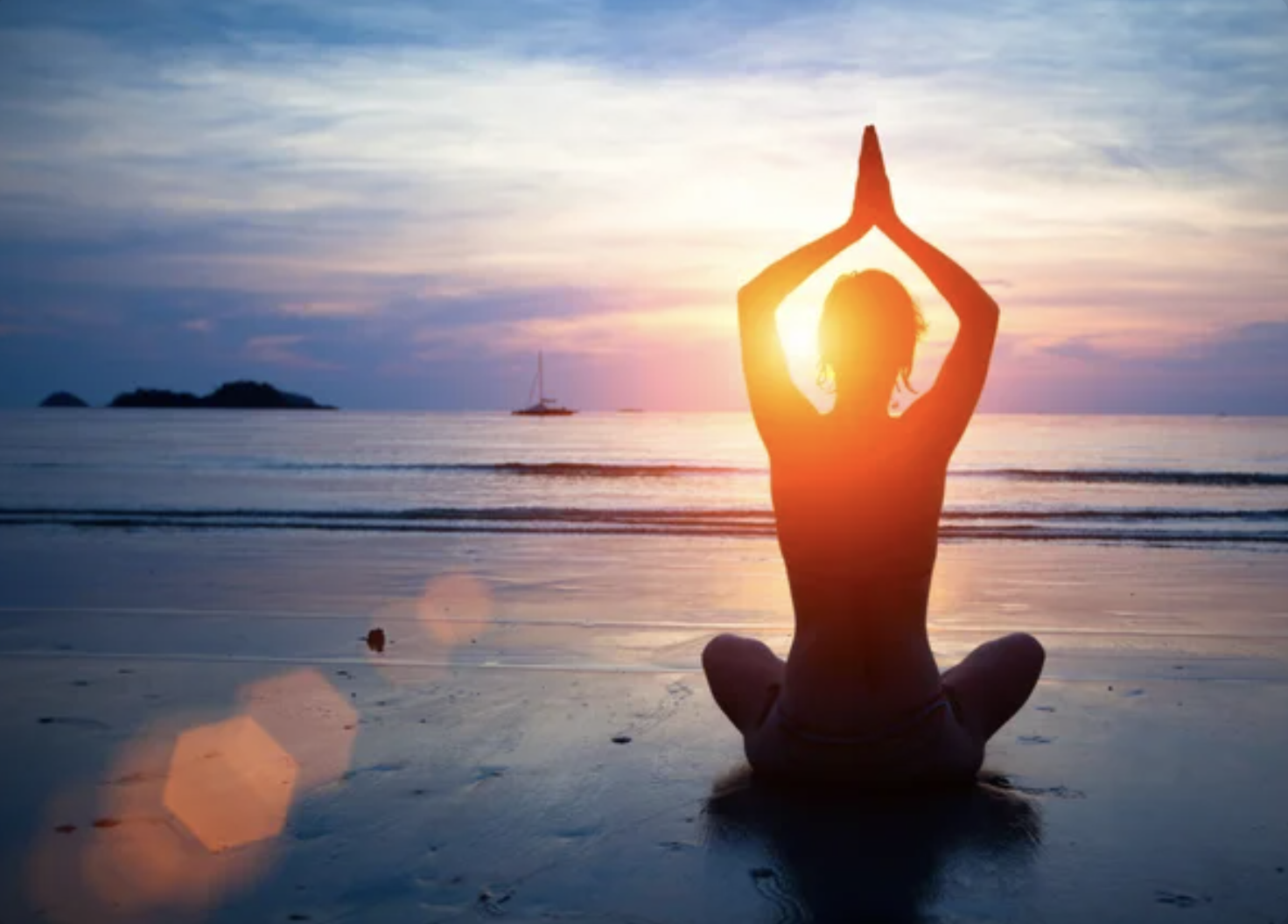 Persona practicando yoga frente al mar al atardecer